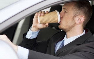 man drinking coffee while driving the car